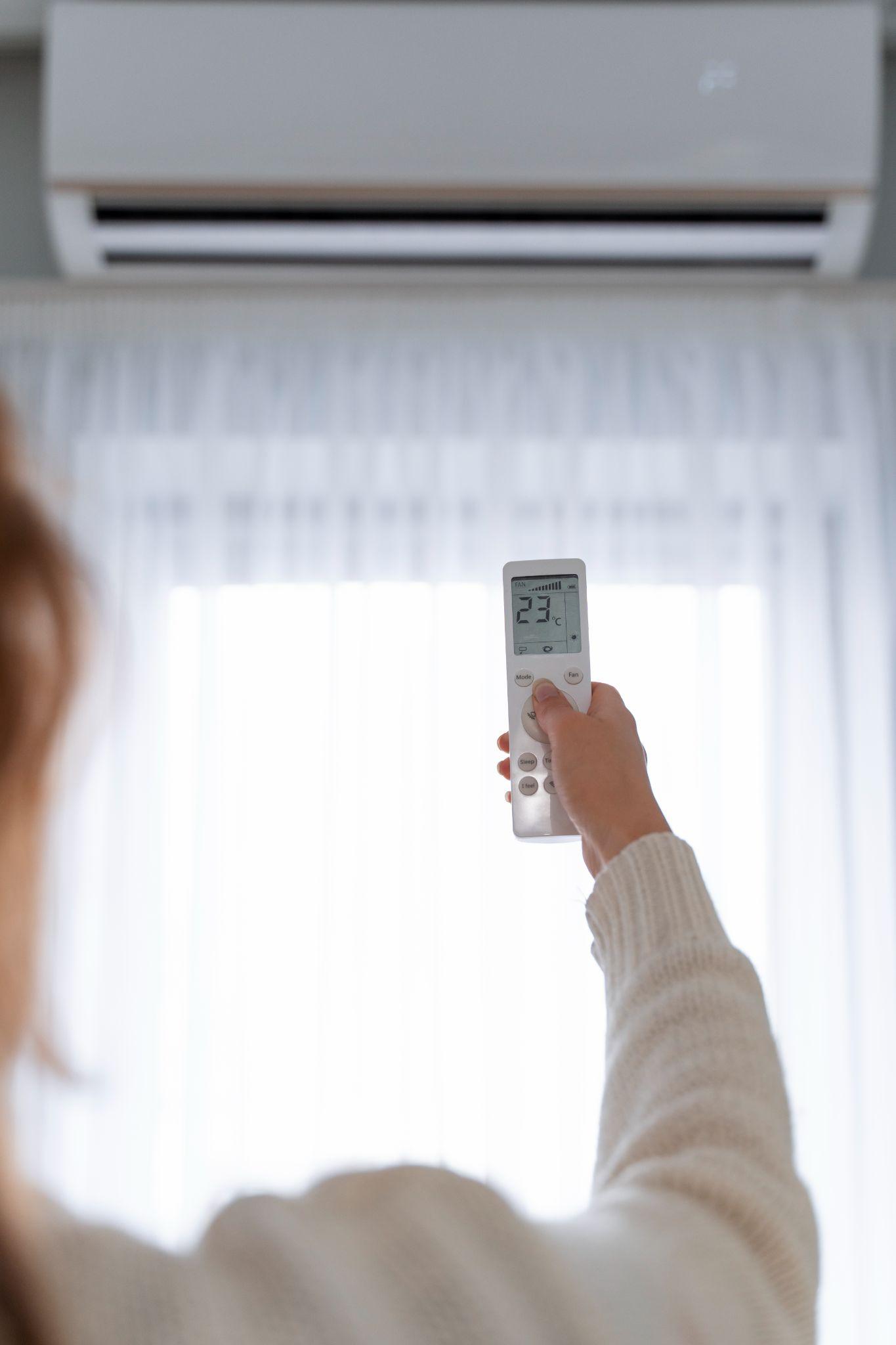 Pessoa ajustando a temperatura do ar-condicionado com o controle remoto